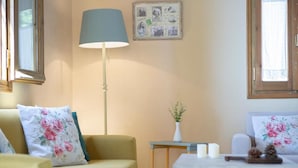 A room with a sofa, a table with candles, a lamp, and a wall-mounted photo collage.