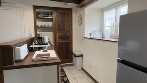 Eine kleine Küche mit Toaster, Kaffeemaschine und Mülleimer.