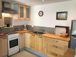 A compact kitchen with a gas stove, wooden cabinets, a sink, and a clock. - Gîte Lamarlière - SAVIGNY-SOUS-FAYE (SAVIGNY-SOUS-FAYE)