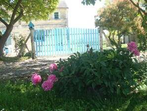 A garden with pink flowers and a blue fence. - La Petite Maison Bleue (SOSSAIS)