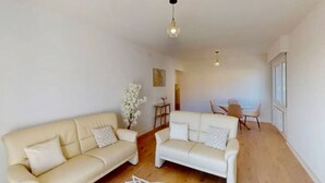 A spacious living area with two sofas, a dining table, and chairs.