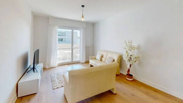A modern living room with a sofa, a TV, a radiator, and a window.