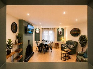A cozy living room with a fireplace, a dining area, and a green sofa. - Triplex 3 bdrms - 6 people - Center & old town - Renovated - Spacious & bright (Boulogne-sur-Mer)
