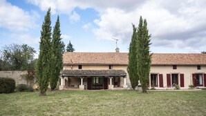 A two-story house with a tiled roof, a covered porch, and a fenced yard. - Le Verger - ANCHE - Gîte (ANCHE)