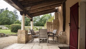 A covered patio with stone pillars, a table, and chairs. - Le Verger - ANCHE - Gîte (ANCHE)