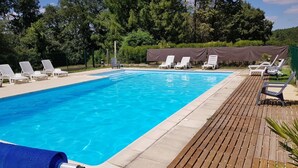 A rectangular swimming pool with clear blue water, surrounded by a wooden deck and white lounge chairs. - Le Verger - ANCHE - Gîte (ANCHE)