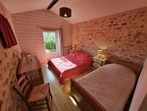 A bedroom with a bed, a desk, a chair, a window, and a lamp. - Gîte de la Vacherie - VIGEANT (LE) (VIGEANT (LE))