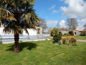 A well-maintained lawn, a palm tree, a greenhouse, and a stone building with a tiled roof. - Gîte de la Vacherie - VIGEANT (LE) (VIGEANT (LE))