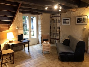 Ein gemütliches Wohnzimmer mit einem Holztisch, einem Computer, einem Stuhl, einer Couch und einem kleinen Tisch mit Tassen.