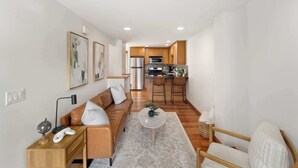 A modern living room with a sofa, coffee table, and a kitchen in the background. - Modern City Retreat • Family Friendly • Free Prkg (Seattle)