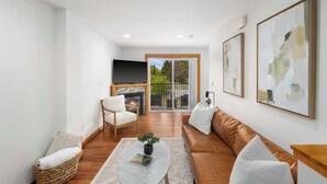 A modern living room with a fireplace, a sofa, a coffee table, and a view of the outdoors. - Modern City Retreat • Family Friendly • Free Prkg (Seattle)