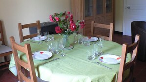 Mesa de comedor lista para cuatro personas, con sillas, un florero y un aparador al fondo.