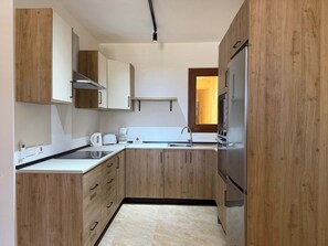 A modern kitchen with wooden cabinets, a built-in oven, a coffee maker, and a sink.