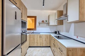 A modern kitchen with wooden cabinets, stainless steel appliances, and a built-in oven.