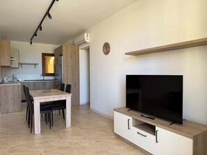 A modern kitchen with a dining area, a flat-screen TV, and a built-in air conditioning unit.