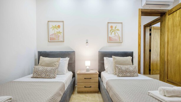 A double room with two beds, a bedside table with a lamp, and a wooden wardrobe.