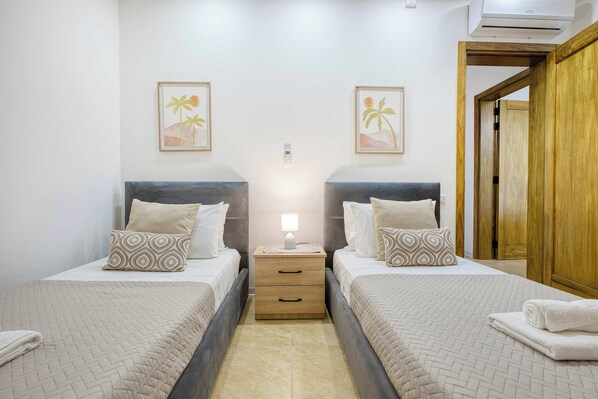 A double room with two beds, a bedside table with a lamp, and a wooden wardrobe.