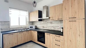Una cocina moderna con armarios de madera, horno empotrado y microondas.