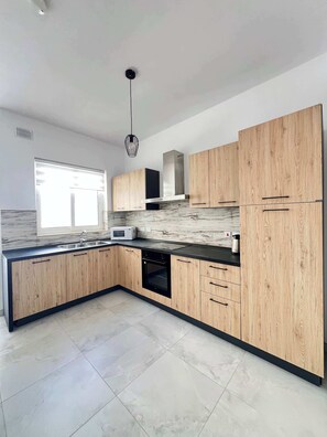 Eine moderne Küche mit Holzausstattung, Backofen und Mikrowelle.