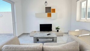 Una sala de estar moderna con un sofá, una mesa de centro, un televisor y una decoración de pared minimalista.
