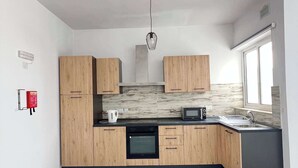 Una cocina moderna con armarios de madera, horno empotrado, microondas y un lavamanos.
