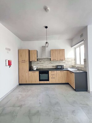 Eine moderne Küche mit Holzausstattung, einem Backofen, einer Mikrowelle und einem Spülbecken.