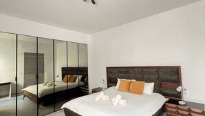Un dormitorio con una cama grande, una mesita de noche, un espejo y una lámpara en el techo.
