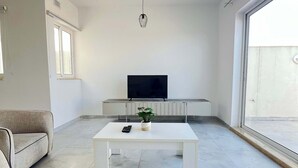 Una sala de estar moderna con un sofá, una mesa de centro, un televisor y una planta.