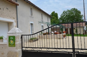 A building with a stone facade, a gated entrance, and a sign indicating it's a Gîte. - Les Lilas - L'HOMMAIZE (LHOMMAIZE)