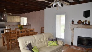 Una sala de estar con sofá, mesa de centro, chimenea y comedor con sillas de madera y una mesa.
