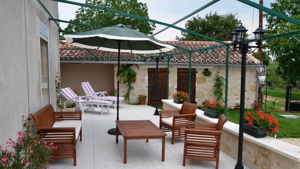 Un patio al aire libre con muebles de madera, una mesa y plantas en macetas.