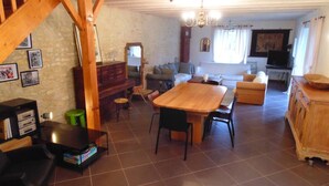 Un vaste espace de vie comprenant une table à manger en bois, des canapés et un escalier.