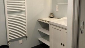 Une salle de bain avec un radiateur blanc, un miroir, un lavabo et un meuble de rangement.