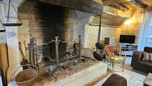 Ein rustikales Interieur mit Kamin aus Stein, Holzbalken und einer gemütlichen Sitzecke.