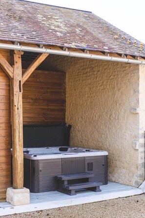 A hot tub outside a building with a wooden structure and stone walls. - Le Gite de l'Erable - MONTAMISE (MONTAMISE)