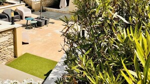 Un patio con mobiliario exterior, una fuente de agua y vistas a un viñedo.