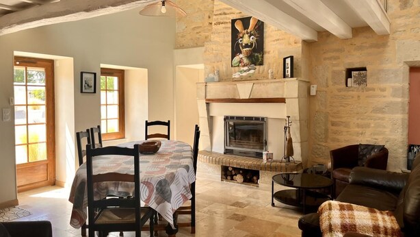 Amplia sala de estar con chimenea, paredes de piedra y una mesa de comedor con sillas.