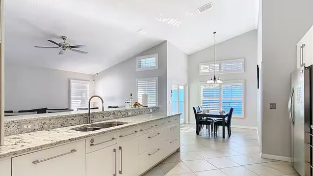 A kitchen with a large island, a dining area with a table and chairs, and a ceiling fan. - Spacious 4/3 Villa w/ Private Pool Near Disney (Davenport)