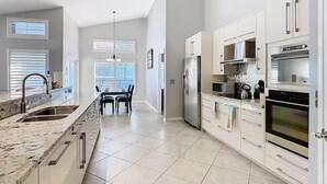 A modern kitchen with white cabinetry, a stainless steel refrigerator, and a built-in oven. - Spacious 4/3 Villa w/ Private Pool Near Disney (Davenport)
