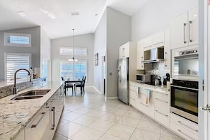 A modern kitchen with white cabinetry, a stainless steel refrigerator, and a built-in oven. - Spacious 4/3 Villa w/ Private Pool Near Disney (Davenport)