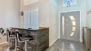 A kitchen with a bar area, a door with a unique design, and a patterned floor. - Spacious 4/3 Villa w/ Private Pool Near Disney (Davenport)