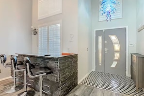 A kitchen with a bar area, a door with a unique design, and a patterned floor. - Spacious 4/3 Villa w/ Private Pool Near Disney (Davenport)