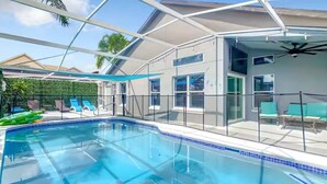 A swimming pool with a glass enclosure, a covered patio area, and a view of the surrounding landscape. - Spacious 4/3 Villa w/ Private Pool Near Disney (Davenport)