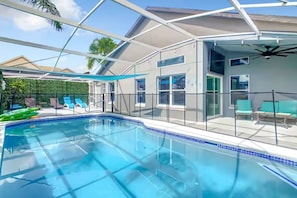 A swimming pool with a glass enclosure, a covered patio area, and a view of the surrounding landscape. - Spacious 4/3 Villa w/ Private Pool Near Disney (Davenport)