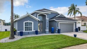 A modern two-story house with a garage, a well-maintained lawn, and a palm tree. - Spacious 4/3 Villa w/ Private Pool Near Disney (Davenport)