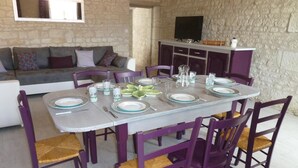 A dining area with a table set for four, surrounded by purple chairs with woven seats. - The 3 Little Pigs (ROCHE-RIGAULT (LA))