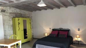 A bedroom with a bed, bedside lamps, a green wardrobe, a wooden table, and a chair. - The 3 Little Pigs (ROCHE-RIGAULT (LA))