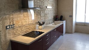 A kitchen with a stone wall, a built-in stove, a sink, and cabinets. - The 3 Little Pigs (ROCHE-RIGAULT (LA))