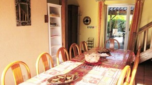 A dining area with a long table, chairs, and a decorative tablecloth. - Le Moulin de Chaume - CHAMPAGNE-SAINT-HILAIRE (CHAMPAGNE-SAINT-HILAIRE)