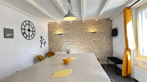 Een eethoek met een stenen muur, een klok en een tafel met gele stoelen.